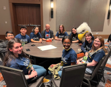 students seated around table at conference. 