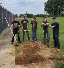 students standing next to big hole they dug